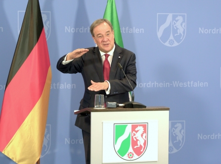 MInisterpräsident Armin Laschet hält gestikulierend eine Rede am Rednerpult stehend, hinter steht die Nordrhein-Westfalen-Flagge, links neben ihm die Deutschland- und die EU-Flagge. 