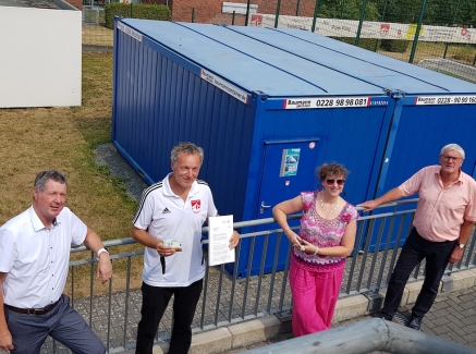 Staatssekretärin Andrea Milz in pinkfarbener Kleidung und dunkler Sonnenbrille steht mit 3 Herren vom Sportverin an einem hellgrauen Geländer.