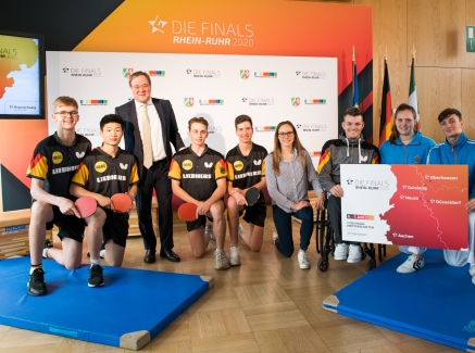 Ministerpräsident Armin Laschet steht mit einem Tischtennisspieler-Team zusammen für ein Portraitbild.