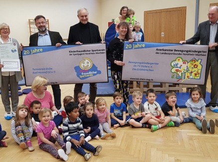 Gruppenfoto mit Staatssekretärin Andrea MIlz, vor ihr sitzen die Kinder der Eichhörnchen-Gruppe auf dem Turnhallenboden.