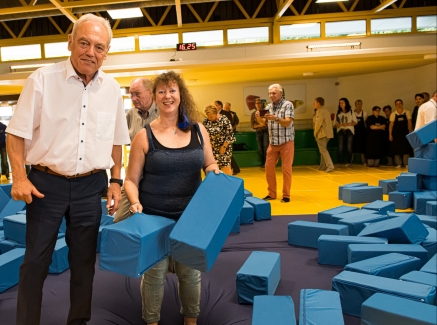 Staatssekretärin Milz mit dem Präsidenten des Landessportbundes NRW, Herrn Walter Schneeloch, an einer Schnitzelgrube gefüllt mit großen, blauen, gepolsterten Quadern.