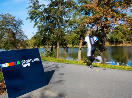 Jogger mit Sportland.NRW-Schild