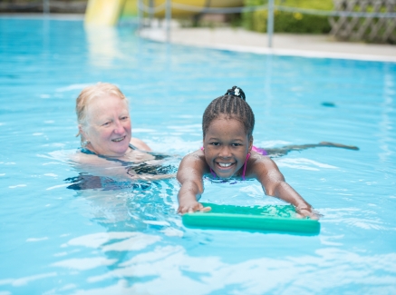 Kind schwimmt mit älterer Dame