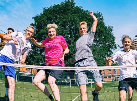 Viele Jungs in Sportkleidung springen vor einem Tennisnetz in die Höhe.