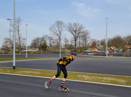 Inline-Skater auf einer asphaltiereten Sportplatzbahn