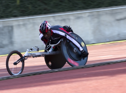 Ein Rennrollstuhlfahrer fährt auf einer Sportbahn.