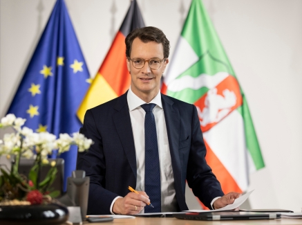 Ministerpräsident Hendrik Wüst vor den Flaggen von Nordrhein-Westfalen, Deutschland und Europa.