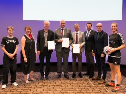 Staatssekretärin Milz steht mit den Preisträgern und den beiden Sportartisten