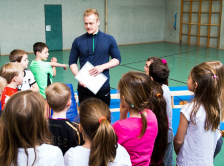 Übungsleiter mit Kindern in Sporthalle