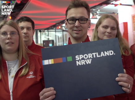 Sportler und Sportlerinnen mit Sportland.NRW-Schild