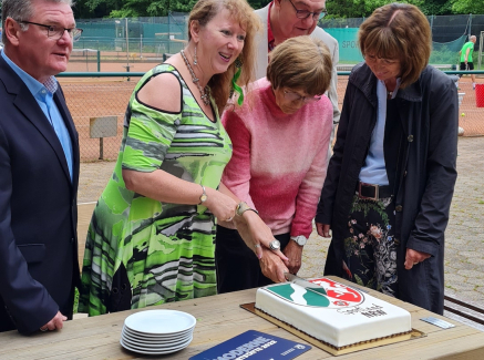 Andrea Milz übergibt Torte auf einem Tennisplatz