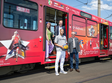 Personen vor einer für die Finals 2023 gebrandeten Straßenbahn