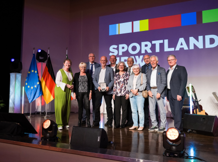 Andrea Milz mit weiteren Personen vor Sportland.NRW-Banner