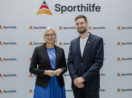 Dr. Christiane Schenderlin und Max Hartung vor einem Sporthilfe-Screen