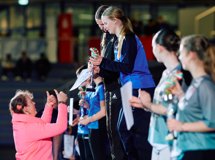 Andrea Milz in rosafarbenem Oberteil übergibt Preise beim Landesfinale