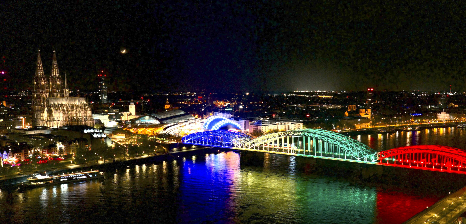 Bunt erleuchtete Brücke vor der Skyline von Köln
