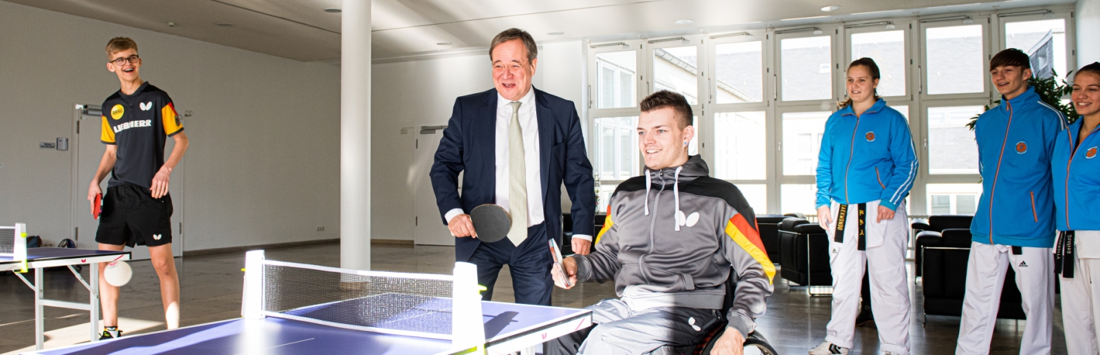 Armin Laschet spielt mit einem jungen Sportler im Rollstuhl Tischtennis.