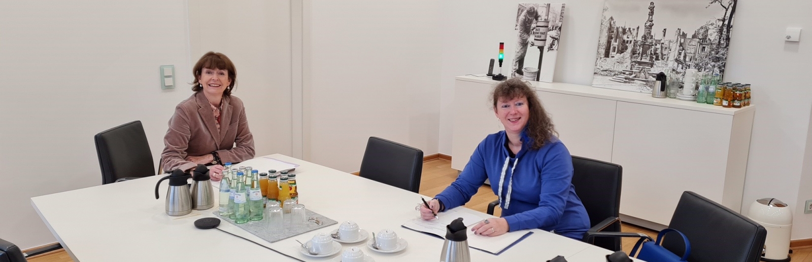 Staatsekretärin Andrea Milz in blauer Strickjacke sitzt mit einer Dame von der Stadt Köln an einem Tisch.