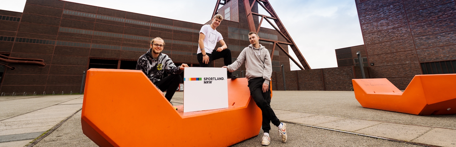 Drei Jugendliche mit Sportland.NRW-Schild auf Zeche Zollverein