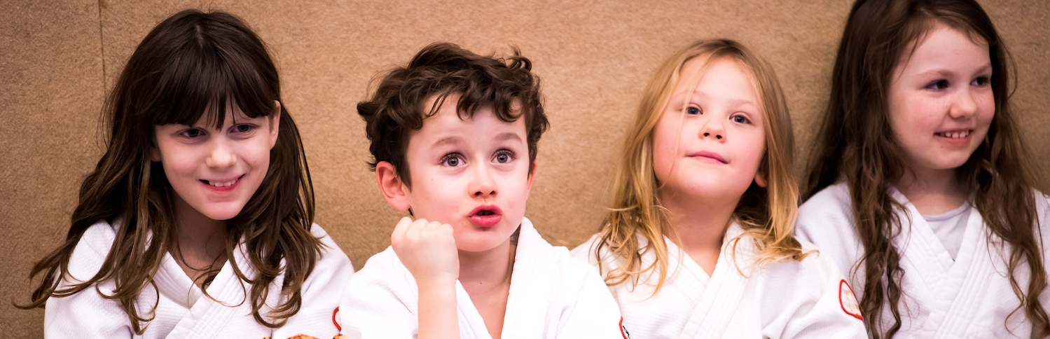 Drei Mädchen und ein Junge in Judo-Bekleidung 