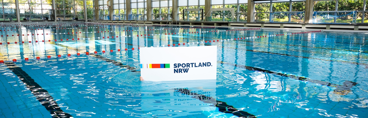 Weißes Sportland.NRW-Schild im Schwimmbecken