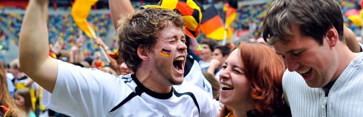 Jubelnde Fans mit Deutschland-Flaggen in einem Stadion.
