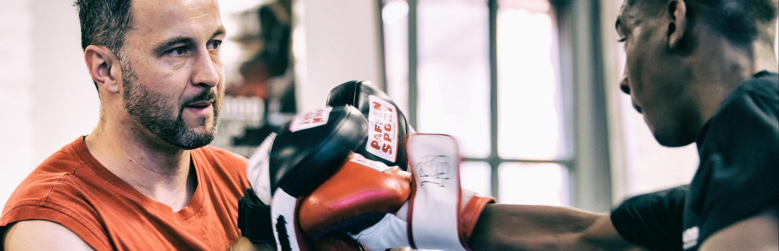 Ein Box-Trainer trainiert mit Boxpranken Schlagübungen mit einem Boxer.