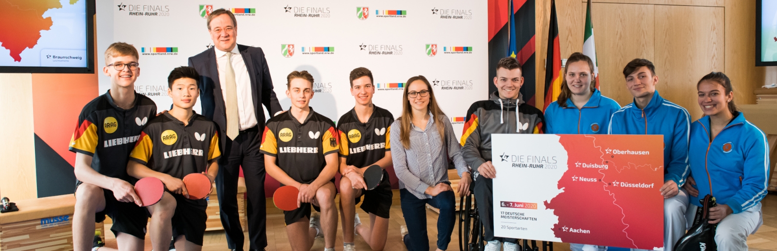 Ministerpräsident Armin Laschet steht mit einem Tischtennisspieler-Team zusammen für ein Portraitbild.