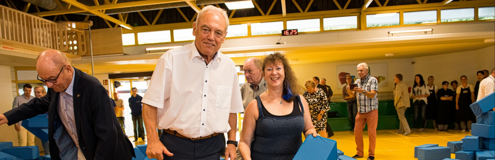 Staatssekretärin Milz mit dem Präsidenten des Landessportbundes NRW, Herrn Walter Schneeloch, an einer Schnitzelgrube gefüllt mit großen, blauen, gepolsterten Quadern.