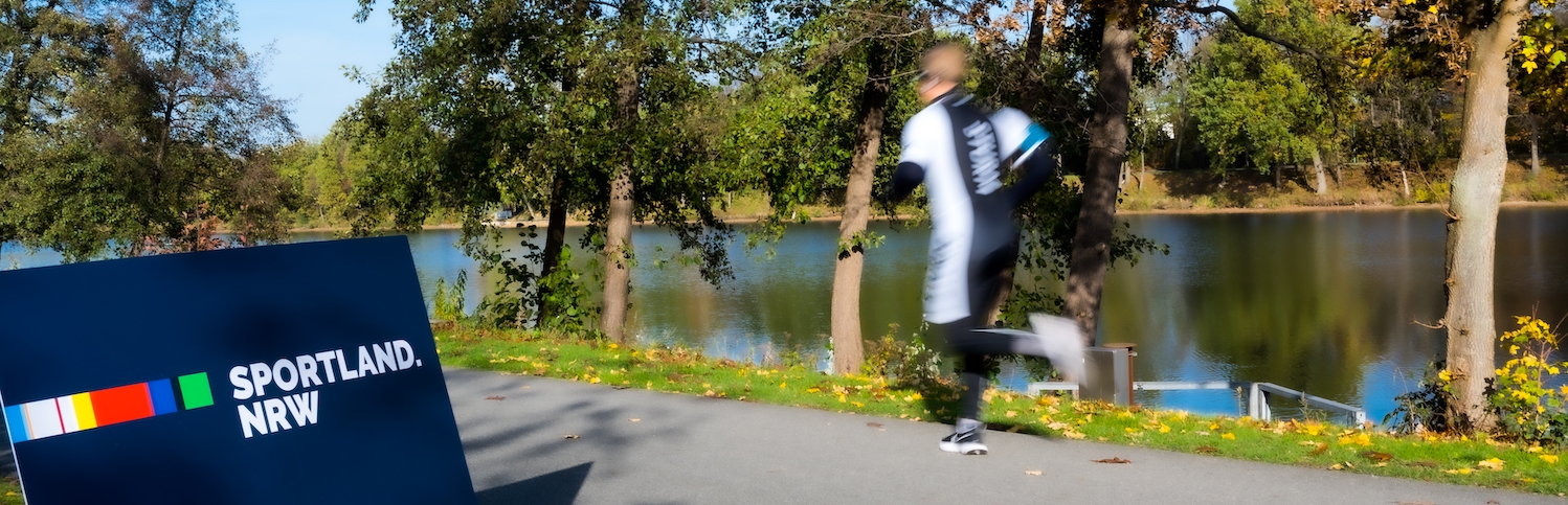 Jogger mit Sportland.NRW-Schild