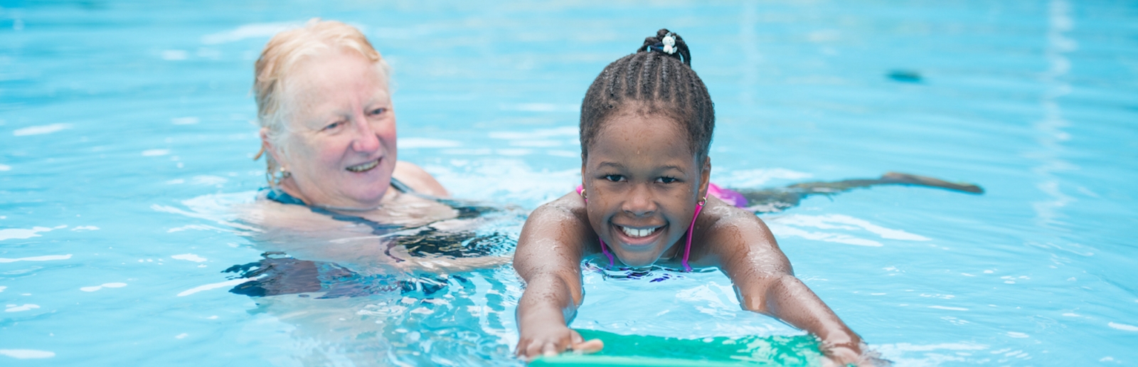 Kind schwimmt mit älterer Dame