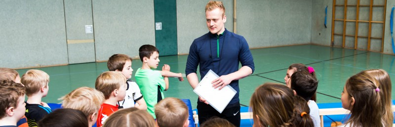 Übungsleiter mit Kindern in Sporthalle