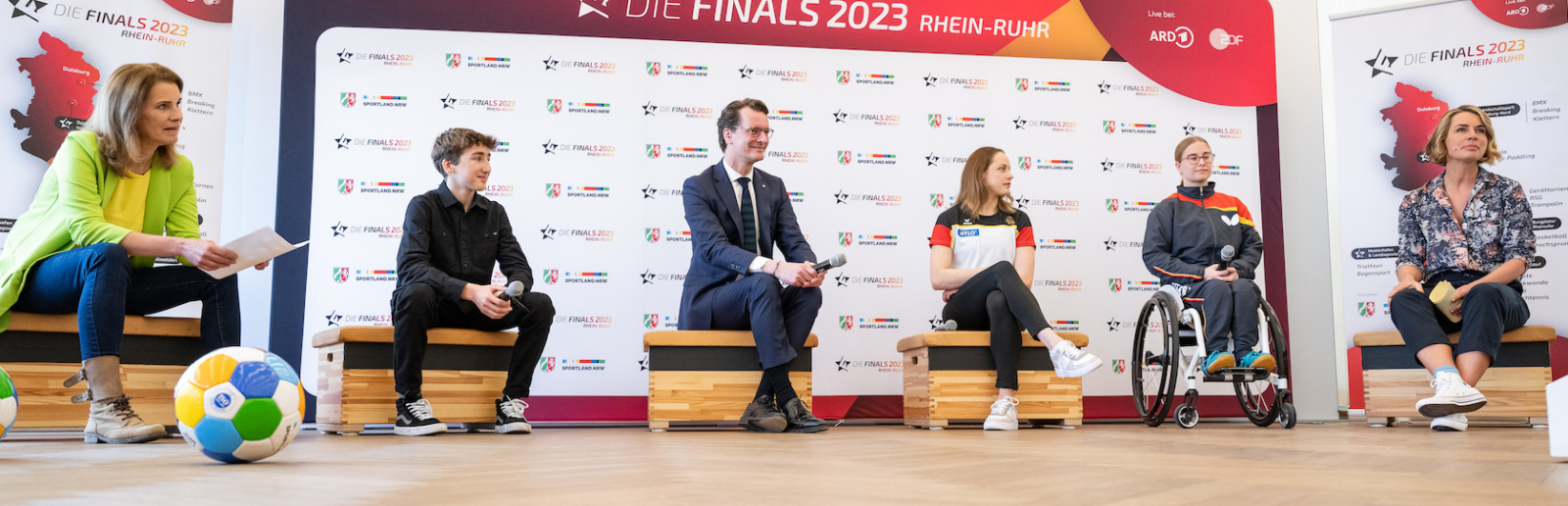 Personen vor Sponsorenwand bei Pressekonferenz