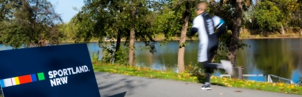 Jogger draußen Sportland.NRW-Schild