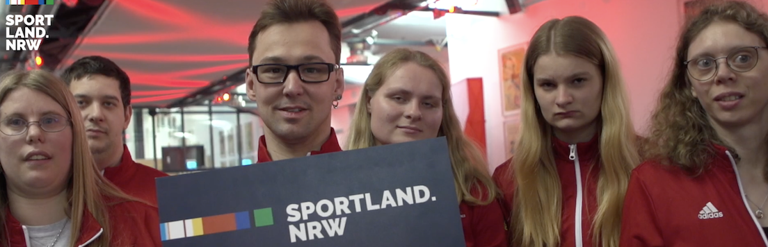 Sportler und Sportlerinnen mit Sportland.NRW-Schild