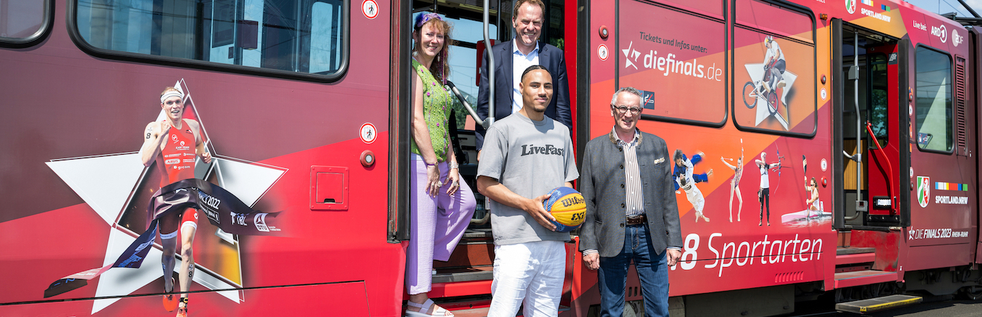 Personen vor einer für die Finals 2023 gebrandeten Straßenbahn