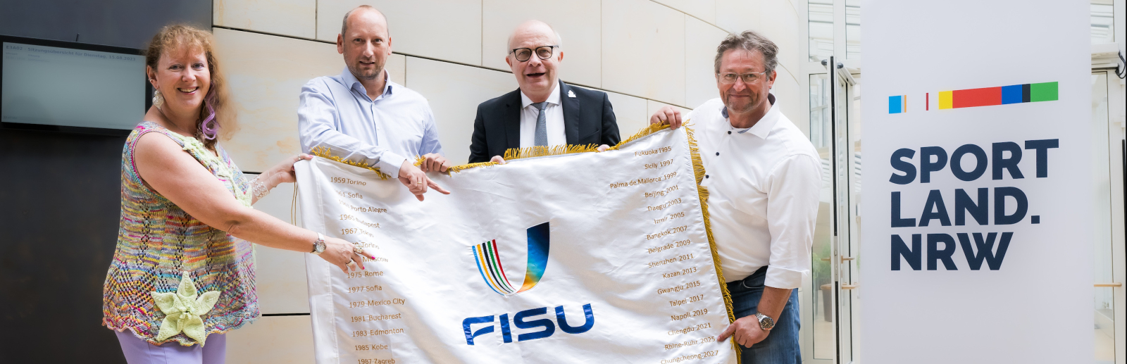 Andrea Milz mit Personen und FISU-Flagge