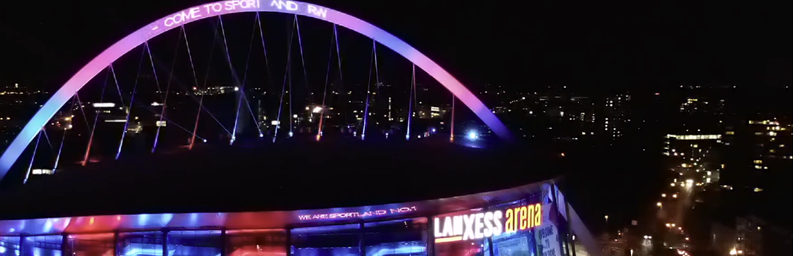 Blick von oben auf die illuninierte Lanxess arena in Köln mit Schriftzug Welcome to Sportland.NRW