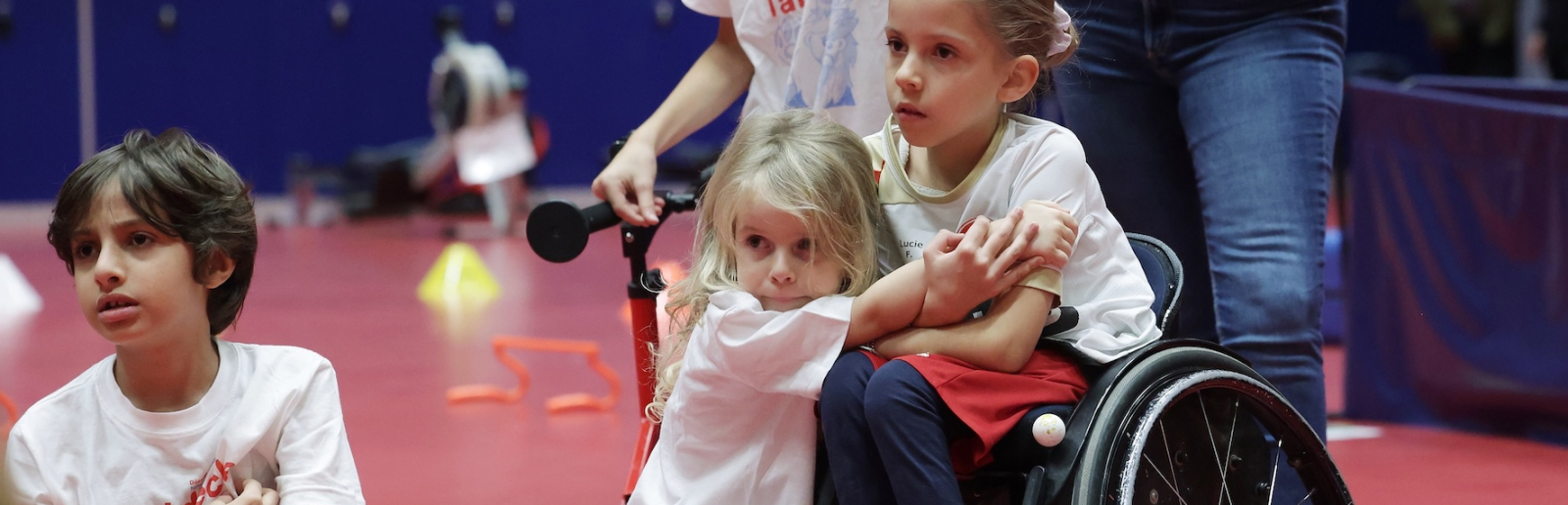 Kinder in einer Halle, ein Kind sitzt in einem Rollstuhl