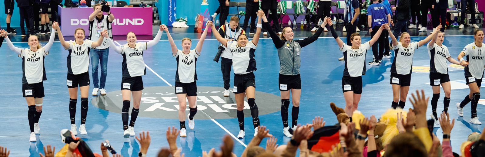 Handballerinnen verbeugen sich vor dem Publikum auf der Tribüne