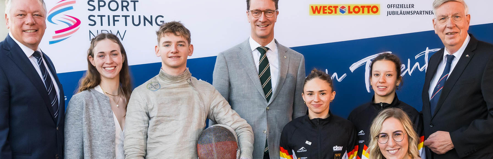 Acht Personen beim Jubiläum der Sportstiftung vor einem Banner
