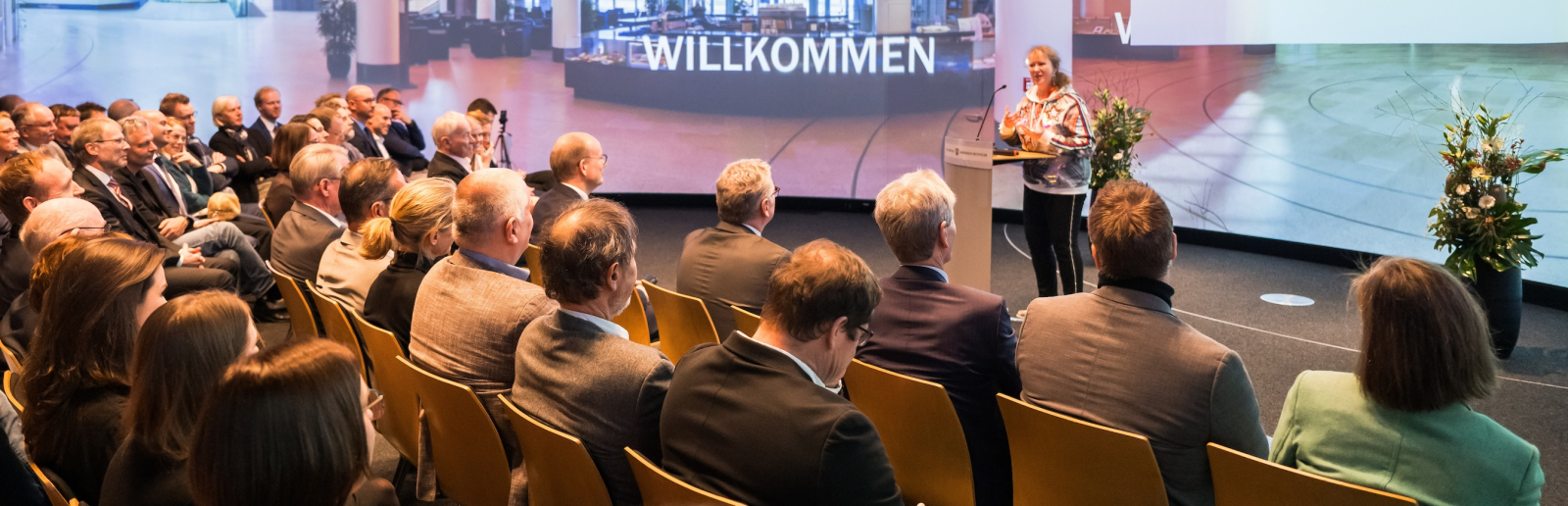 Andrea Milz auf einer Bühne mt Sitzreihen voller Personen