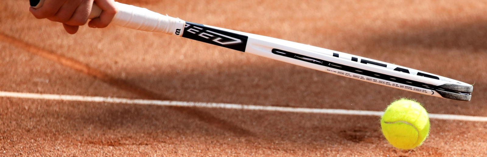 Tennisschläger und Ball auf roter Asche