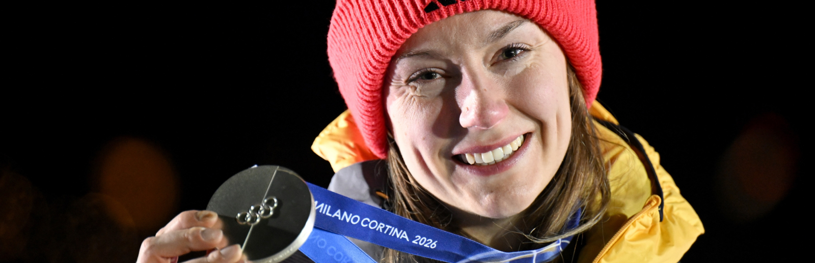 Laura Nolte hält Silbermedaille, vor dunklem Hintergrund