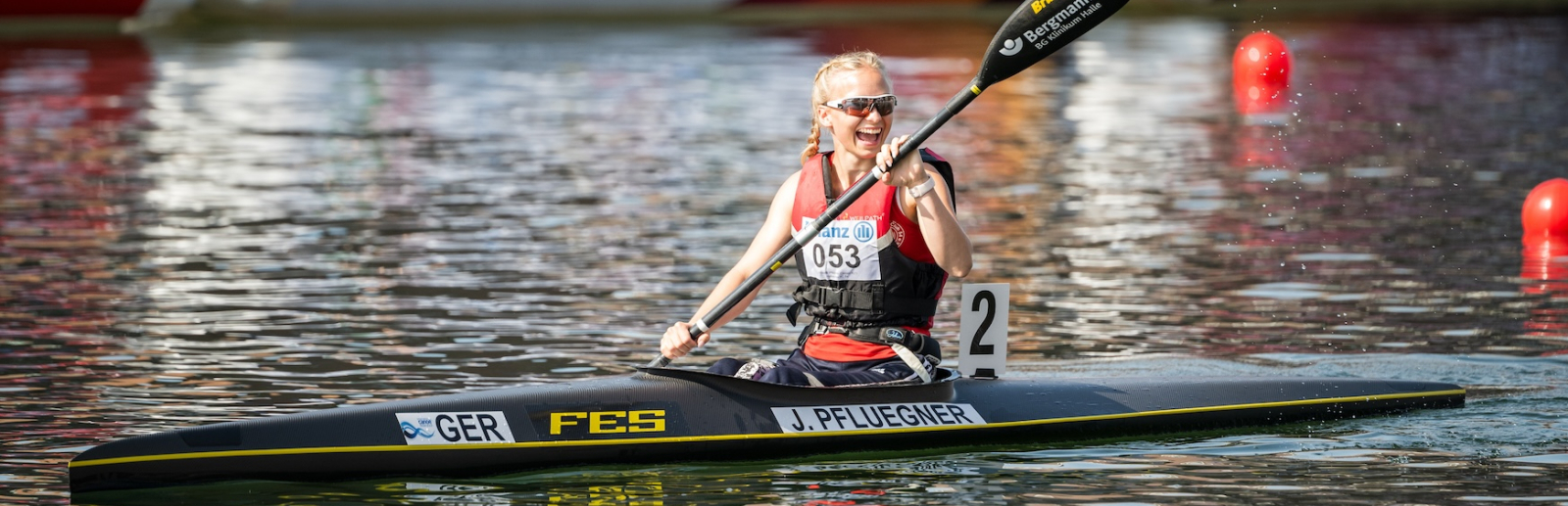 Kanufahrer auf dem Wasser mit einem Banner "Sportland.NRW" im Hintergrund