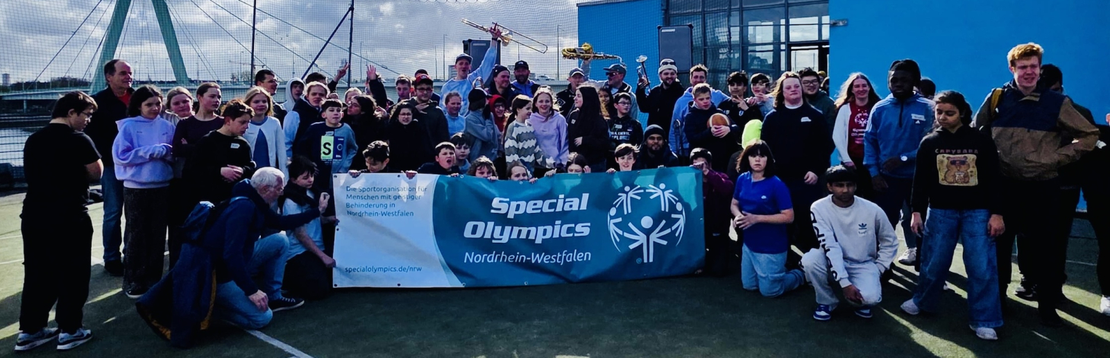 Gruppe von Kindern und Schulkindern auf einem Ballfeld vor blaumen Himmel