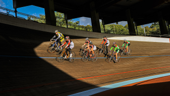 Sieben Rennradsportler fahren mit ihren Rennrädern auf der Radrennbahn des Kölner Radstadions im Sportpark Müngersdorf.