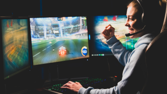 Junge Frau vor zwei Computer-Bildschirmen