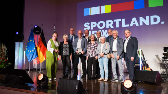 Andrea Milz mit weiteren Personen vor Sportland.NRW-Banner
