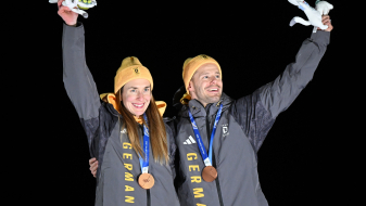 Jacqueline Pfeifer und Christopher Grotheer mit Medaillen um den Hals vor dunklem Hintergrund